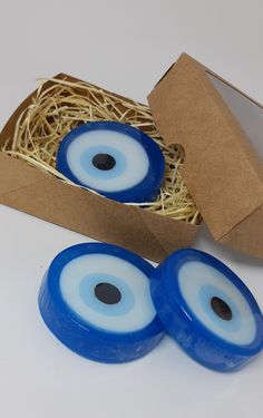 two blue eyeballs in a cardboard box next to some straw on the floor and one is empty