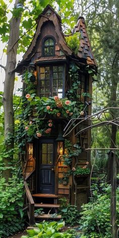 a small wooden house in the woods with flowers growing on it's roof and windows