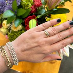 a woman's hand with three different bracelets and two rings on her wrist