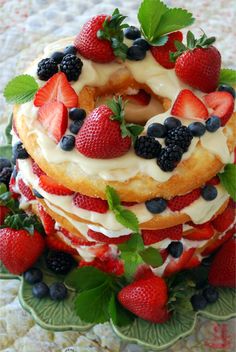 a cake with strawberries and blueberries is on a green plate next to berries