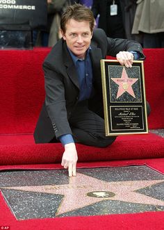 a man kneeling down next to a star on the hollywood walk of fame with his hand out