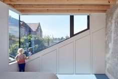 two people are standing at the top of a stair case in a bedroom with large windows