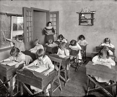 an old black and white photo of children at desks