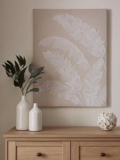 two white vases sitting on top of a wooden dresser next to a large painting