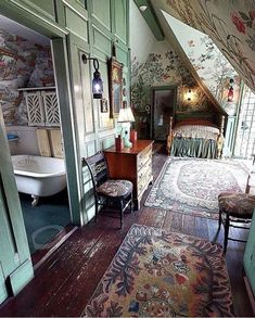 an old fashioned bedroom is decorated with floral wallpaper and rugs, along with a claw foot tub