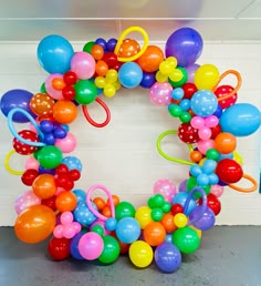 a bunch of balloons that are in the shape of a wreath on top of a wall