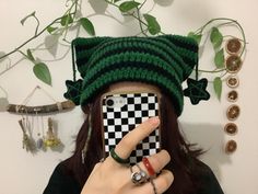 a woman taking a selfie with her cell phone wearing a green knitted hat