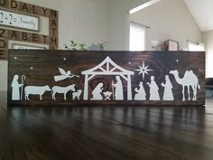 a wooden sign with the silhouettes of people and nativity scene on it sitting on a wood floor