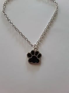 a small dog paw charm on a silver chain with a black cat's paw in the center