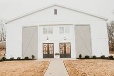 a large white barn with two doors and windows