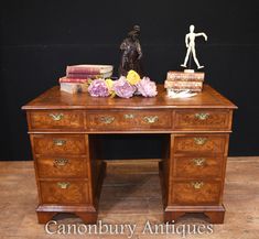 an antique desk with books and figurines on it, against a black background