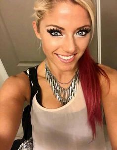 a woman with long red hair and black eyeliners smiles at the camera while wearing silver necklaces