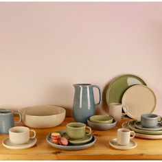 a wooden table topped with plates and cups