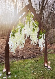 a wooden arch with candles and flowers hanging from it's sides in the grass