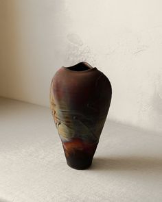 a brown vase sitting on top of a white surface next to a window sill