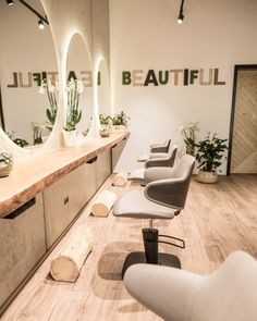 a hair salon with chairs and mirrors in front of the counter, along with succulents