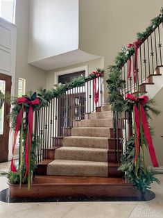 the stairs are decorated with christmas garland and red bows for an elegant entrance to this home