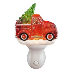 a red truck with a christmas tree on the hood sitting on top of a white knob