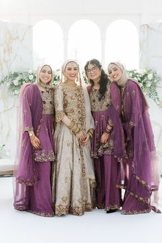 Bride stands with her bridesmaids who wear purple saree's complete with gold embellishment Bridesmaid Pakistani Dresses, Brides Sisters Dress, Bride Sisters Dress, Wedding Cousins Dress, Pakistani Wedding Outfits Sisters Bridesmaid Dresses, Pakistani Wedding Outfits Sisters Ideas, Gold Wedding Bridesmaid Dresses, Wedding Dress For Sister, Nikkah Dress For Sisters