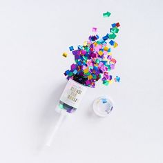 a bottle filled with colorful confetti and sprinkles on top of a white surface