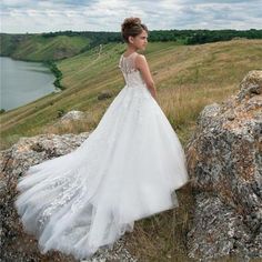 a woman in a wedding dress standing on top of a hill