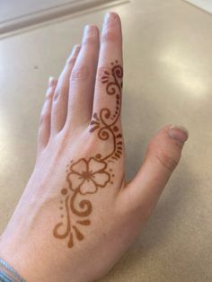 a woman's hand with a henna tattoo on her left wrist and fingers