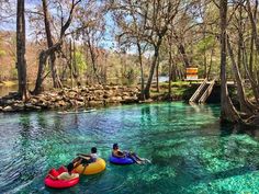 two people on inflatables floating down a river surrounded by trees and rocks