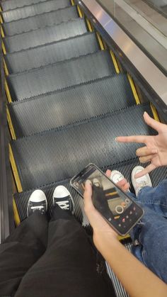 a person on an escalator using a cell phone and pointing at the screen