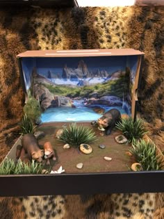 an open box with animals in it sitting on a leopard print couch next to rocks and plants