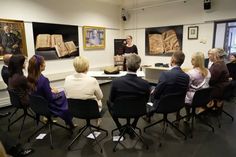 a group of people sitting around a table in front of pictures on the wall behind them