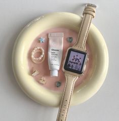 an apple watch sits on top of a plate with other items around it, including bracelets and rings