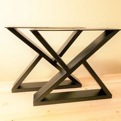 a glass table with black metal legs on a wooden floor