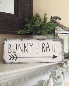 a wooden sign that says bunny trail on it next to a potted plant and mirror