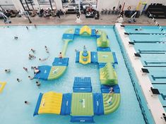 an indoor swimming pool filled with people and inflatable water slides on top of it