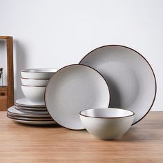 a stack of white plates and bowls on a wooden table