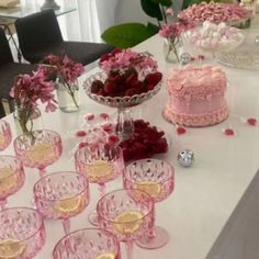 a table topped with lots of pink cakes and glasses