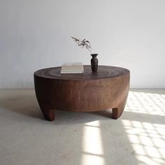 a wooden table with a vase on it and a book sitting on top of it