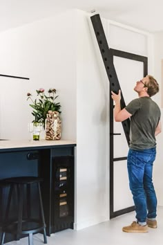 a man standing in front of a black door holding a large piece of furniture up against the wall