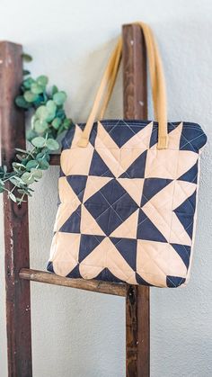 a black and white bag sitting on top of a wooden chair next to a plant