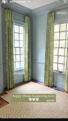 a living room with blue walls and green drapes on the window sill, along with a rug that says happy things happening here