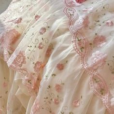 pink and white bedding with floral embroidered on the bottom, along with ruffled edges