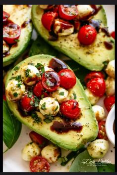 avocados with tomatoes, mozzarella and other toppings on a plate