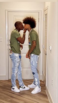 two people standing in front of a door with their faces close to each other and one has his mouth open