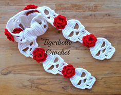 a crocheted headband with red roses on it sitting on a wooden surface