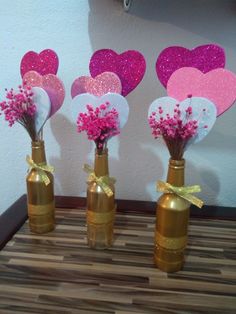 three vases with flowers in them and hearts hanging on the wall behind them for valentine's day