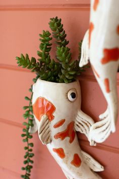 a fish shaped planter hanging from the side of a wall