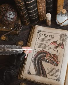 an old book with a dragon drawn on it next to some books and other items