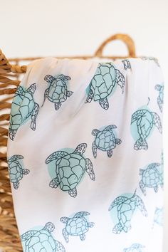 a blanket with sea turtles on it is sitting in a wicker basket next to a wall