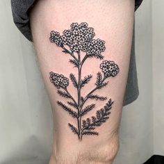 a black and white flower tattoo on the right thigh, with small flowers growing out of it