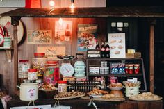 an assortment of food is displayed on a table in front of a wall with posters and lights